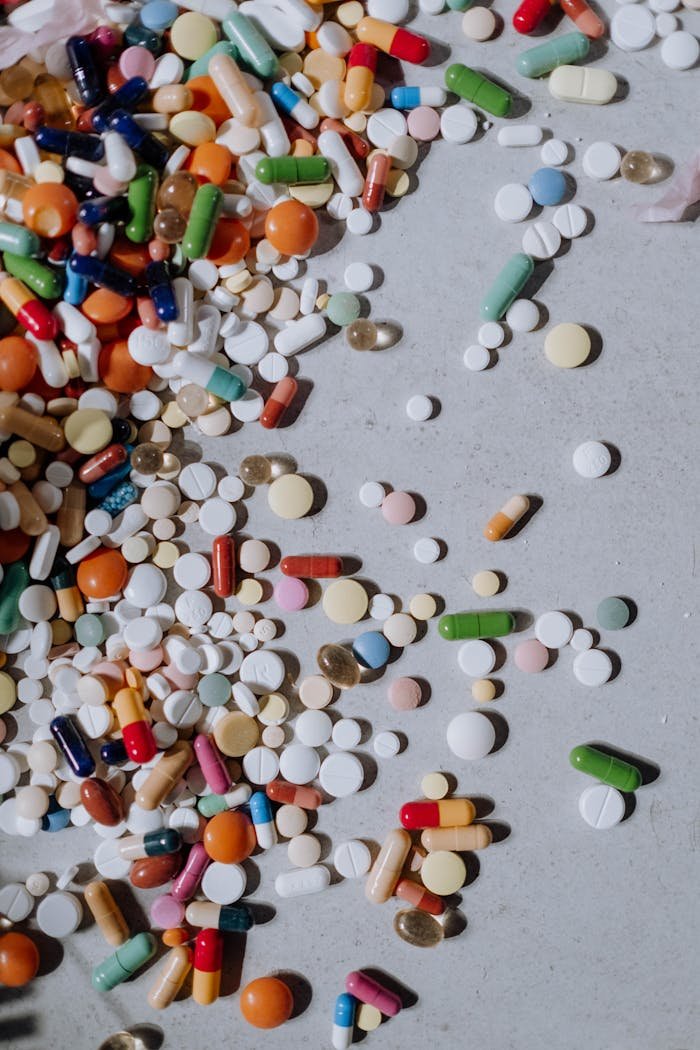 A diverse mix of pills and capsules scattered on a flat surface.